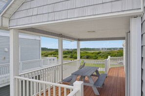 A covered outdoor deck with a picnic table and white railings. - Dog-friendly oceanfront escape (North Topsail Beach)