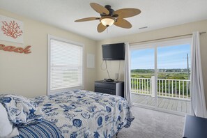 A bedroom with a bed, a ceiling fan, a TV, and a balcony with a view. - Dog-friendly oceanfront escape (North Topsail Beach)