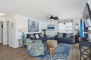A living room with a blue sofa, patterned armchair, and a decorative rug. - Dog-friendly oceanfront escape (North Topsail Beach)