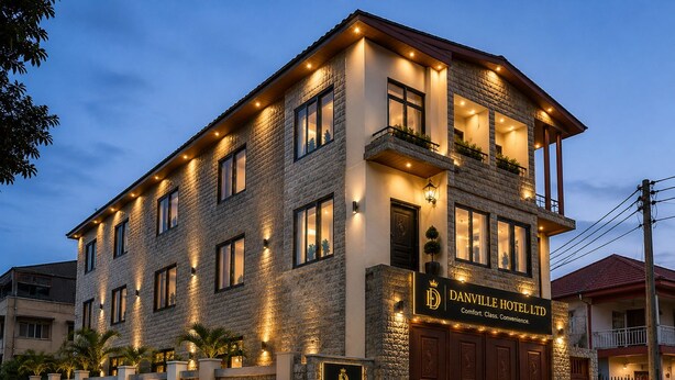 Een meerhoog hotel met een stenen gevel, verlichte ramen en een naamplaatje.