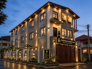 A two-story hotel with a stone facade, multiple windows, and a signboard.