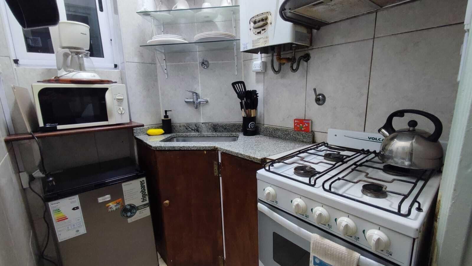 A compact kitchen with a gas stove, a microwave, and a coffee maker.