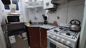 A compact kitchen with a gas stove, a microwave, and a coffee maker. - aSDSasd (San Justo)