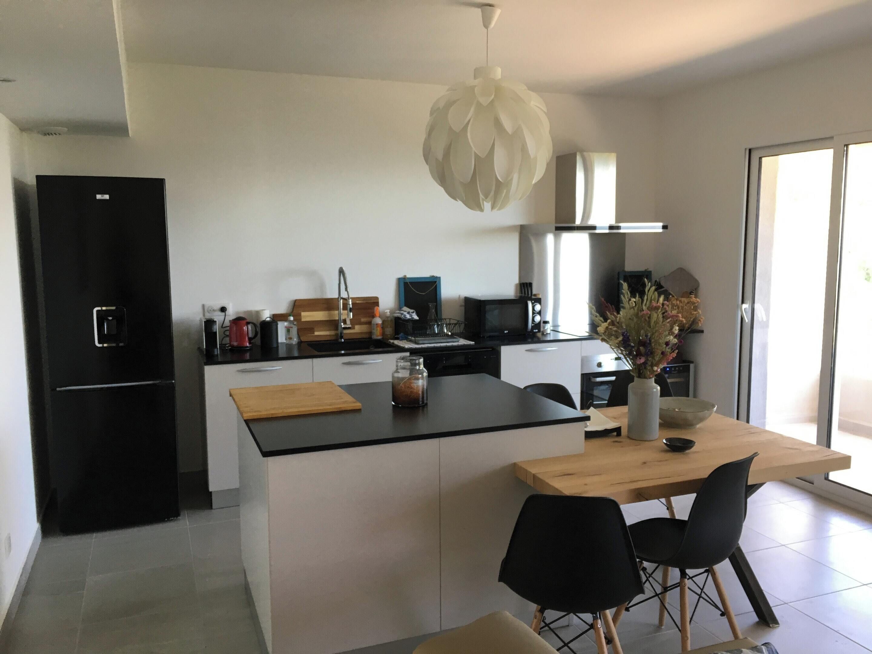 Eine moderne Küche mit einer zentralen Kochinsel, schwarzen Geräten und einem Holzespeise Tisch mit Stühlen.