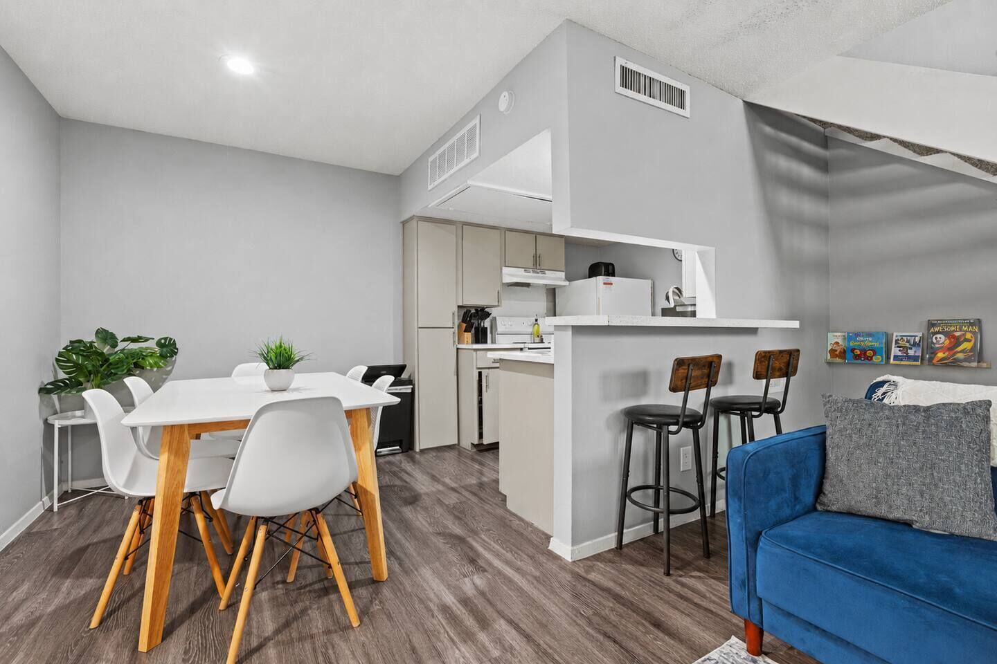 Un espace de vie compact comprenant un coin repas, une kitchenette et un canapé bleu.