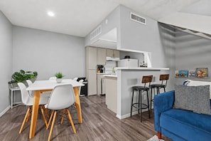 A compact living space with a dining area, kitchenette, and a blue sofa. - Cozy 1BR in a convenient Austin location. (Austin)