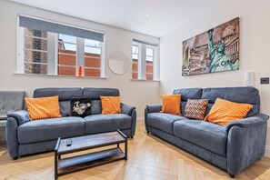 A modern living room with two grey sofas, a coffee table, and a large painting of the Statue of Liberty. - Modern Flat In Jewellery Quarter Free Parking (Birmingham)