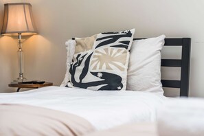 A bed with white bedding and two decorative pillows with abstract patterns. - Modern Flat In Jewellery Quarter Free Parking (Birmingham)