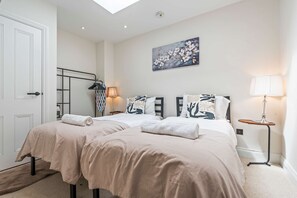 A bedroom with a double bed, a side table, a lamp, and a painting on the wall. - Modern Flat In Jewellery Quarter Free Parking (Birmingham)