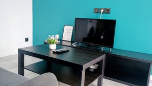 A modern living room with a flat-screen TV, a coffee table, a potted plant, and a framed certificate on the wall. - Appartement Tout Equipe a Lens Avec Parking Gratuit Proche du Louvre Lens (Lens)