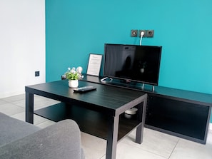 Ein modernes Wohnzimmer mit Flachbildfernseher, Couchtisch, Topfpflanze und gerahmtem Zertifikat an der Wand.