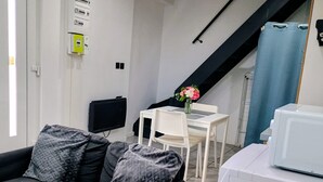 Ein modernes Wohnzimmer mit Sofa, Flachbildfernseher, Esstisch mit Stühlen und einer Treppe.