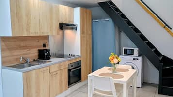 A compact kitchen with wooden cabinets, a sink, a stove, and a microwave.