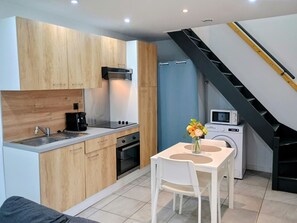 Cozinha compacta com armários de madeira, pia, fogão e micro-ondas.