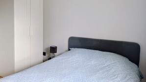 Ein Schlafzimmer mit Bett, Schrank und Nachttisch mit Lampe.