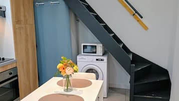 A modern kitchen with a built-in oven, a washing machine, and a microwave on a small table.