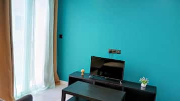 A living room with a flat-screen TV on a black stand, a small table, and a sofa.