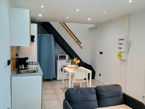 Um espaço de estar compacto com cozinha compacta, área de refeições e escada.