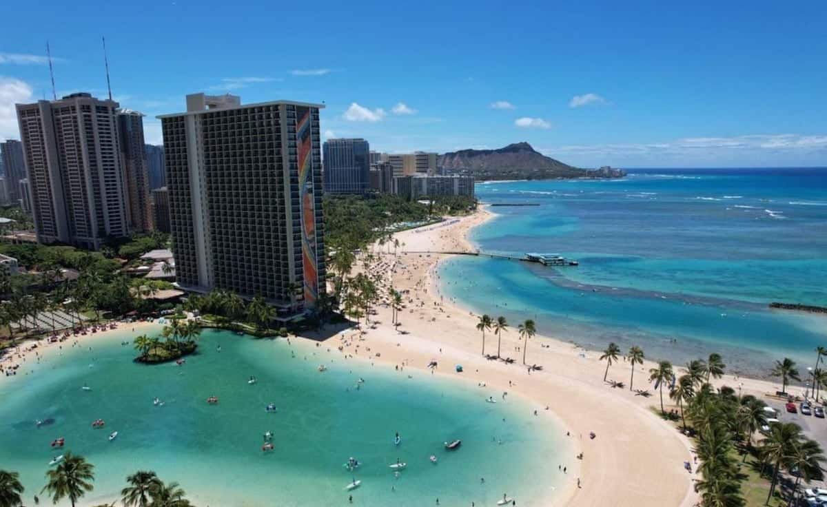 Un paysage urbain côtier avec une plage, des immeubles de grande hauteur et une eau bleue et limpide.