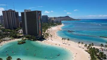Un paysage urbain côtier avec une plage, des immeubles de grande hauteur et une eau bleue et limpide.