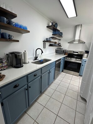 Eine moderne Küche mit blauen Schränken, einer Edelstahl-Spüle, einer Mikrowelle und einem eingebauten Backofen.