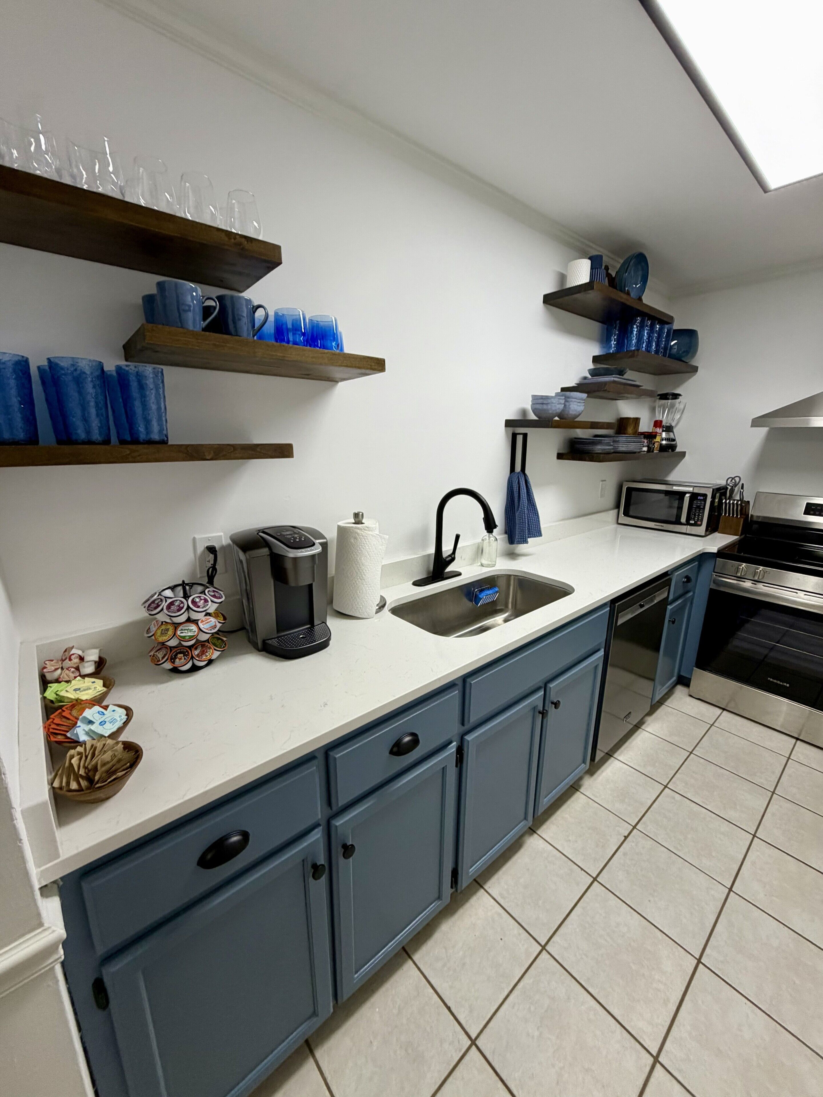 A kitchen with blue cabinets, a microwave, a coffee maker, and various kitchen utensils.