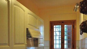 A compact kitchen with white cabinetry, a window with wooden shutters, a built-in stove, and a countertop with a knife block. - Homerez - House in Gattaia with pool (Gattaia)