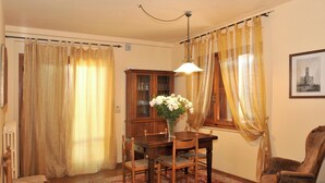 A dining room with a wooden table, chairs, a vase with flowers, a cabinet, and a chair. - Homerez - House in Gattaia with pool (Gattaia)