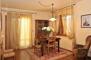 A dining room with a wooden table, chairs, a vase with flowers, a cabinet, and a chair. - Homerez - House in Gattaia with pool (Gattaia)