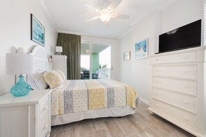 Une chambre à coucher avec un lit, une commode, un téléviseur et un ventilateur de plafond.