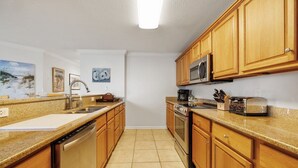 A kitchen with wooden cabinets, a stainless steel dishwasher, a microwave, and a stove. - Hooked Bliss|Bay Views+Boat Slip+Beach Access (Gulf Shores)