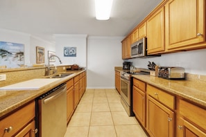 A kitchen with wooden cabinets, a stainless steel dishwasher, a microwave, and a stove. - Hooked Bliss|Bay Views+Boat Slip+Beach Access (Gulf Shores)