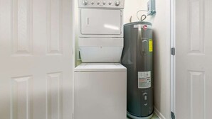 A laundry room with a washer and dryer, a water heater, and a door. - Hooked Bliss|Bay Views+Boat Slip+Beach Access (Gulf Shores)