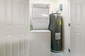 A laundry room with a washer and dryer, a water heater, and a door. - Hooked Bliss|Bay Views+Boat Slip+Beach Access (Gulf Shores)
