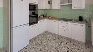 A kitchen with white cabinets, a refrigerator, an oven, a microwave, a cutting board, and a sink. - Moelda Home | Milan-Malpensa MXP 15′ Milan-Fiera (legnano)