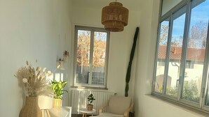 A room with a large window, a wicker hanging light, a white sofa, and a small table with a plant. - Moelda Home | Milan-Malpensa MXP 15′ Milan-Fiera (legnano)