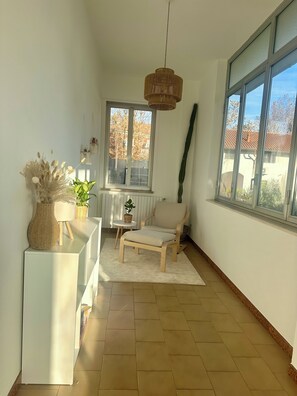 A room with a large window, a wicker hanging light, a white sofa, and a small table with a plant. - Moelda Home | Milan-Malpensa MXP 15′ Milan-Fiera (legnano)