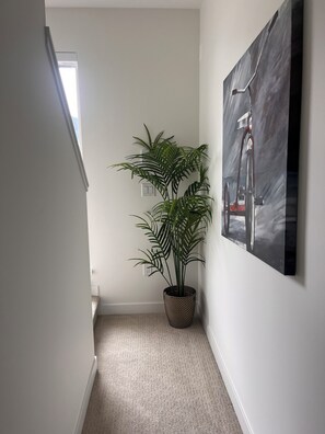 A hallway with a potted plant and a painting on the wall. - Modern Mountain Retreat with Lake Views | 90+ stay (Britannia Beach)