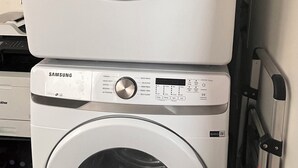 Een wasmachine en droger in een apparaat, met bedieningspaneel en een deur.