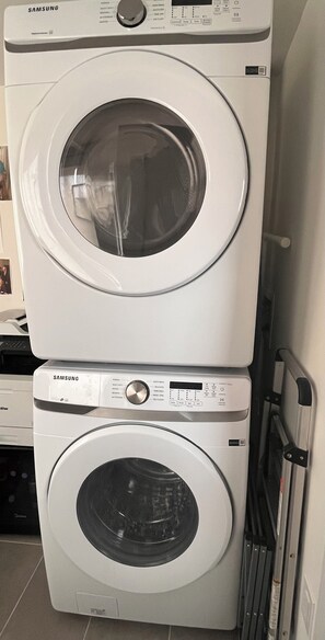 A stacked washer and dryer unit with control panels and a door. - Modern Mountain Retreat with Lake Views | 90+ stay (Britannia Beach)
