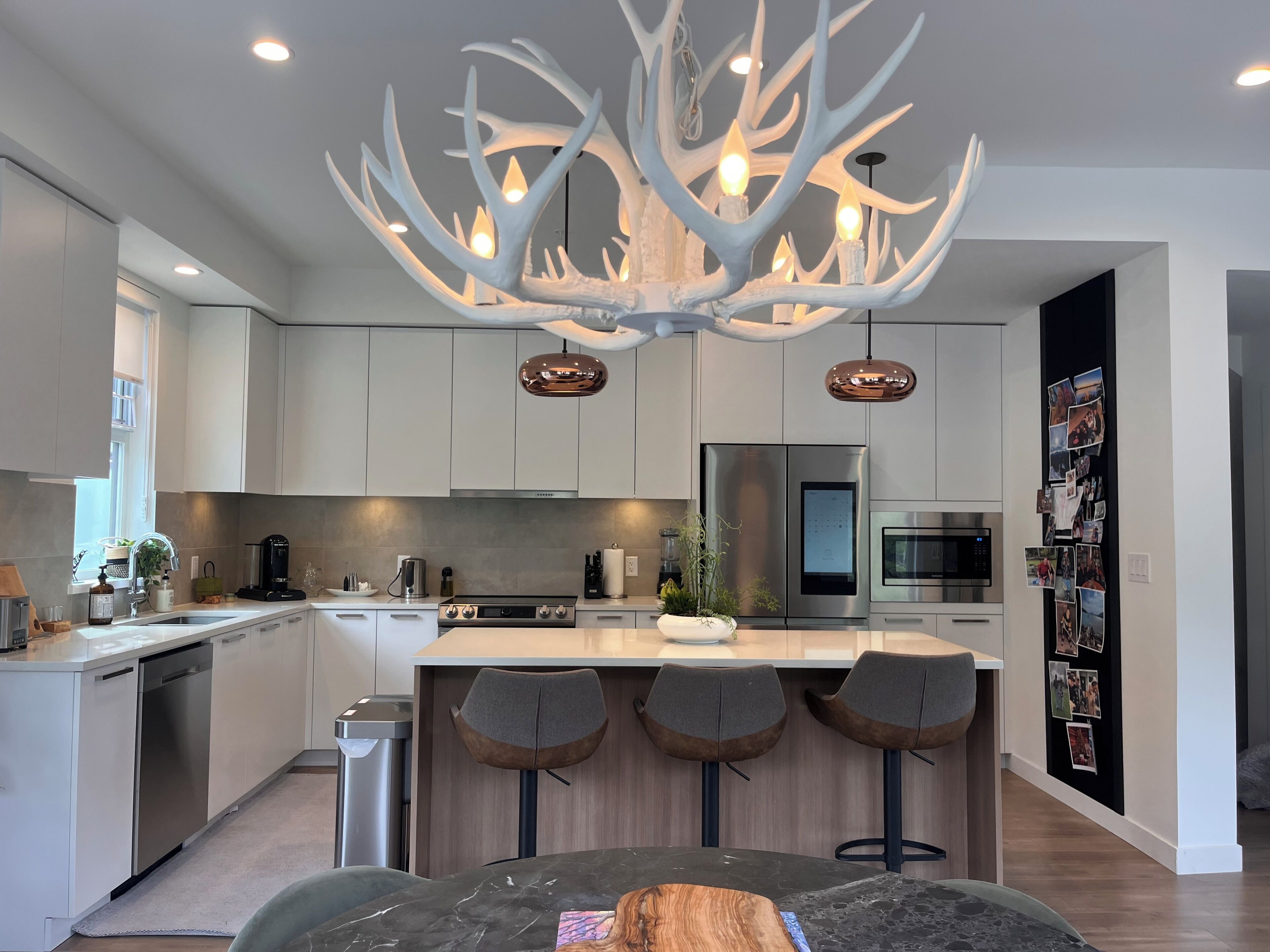 Una cocina moderna con una isla central, electrodomésticos de acero inoxidable y una lámpara original con forma de asta de ciervo.