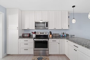 Cocina moderna con armarios blancos, electrodomésticos de acero inoxidable y encimera de granito.