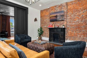 Ein modernes Wohnzimmer mit Backsteinwand, Kamin und Stadtbildgemälde.