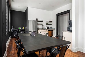 A modern kitchen with a dining area, featuring a large table and chairs, a built-in oven, and a coffee machine. - The Stables | Walkable, MiniGolf, Fire Pits, Games (Louisville)
