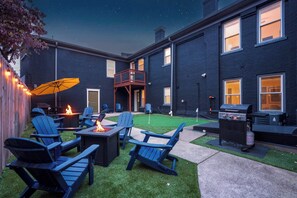 A backyard with a fire pit, outdoor seating, a grill, and a covered patio area. - The Stables | Walkable, MiniGolf, Fire Pits, Games (Louisville)