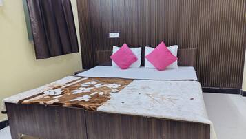A bedroom with a wooden bed, two pillows, a patterned bedspread, and a dark curtain.