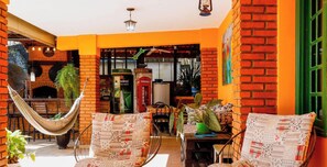 Uma área de estar acolhedora ao ar livre, com uma rede, um muro de tijolos e uma cabine telefônica vermelha.