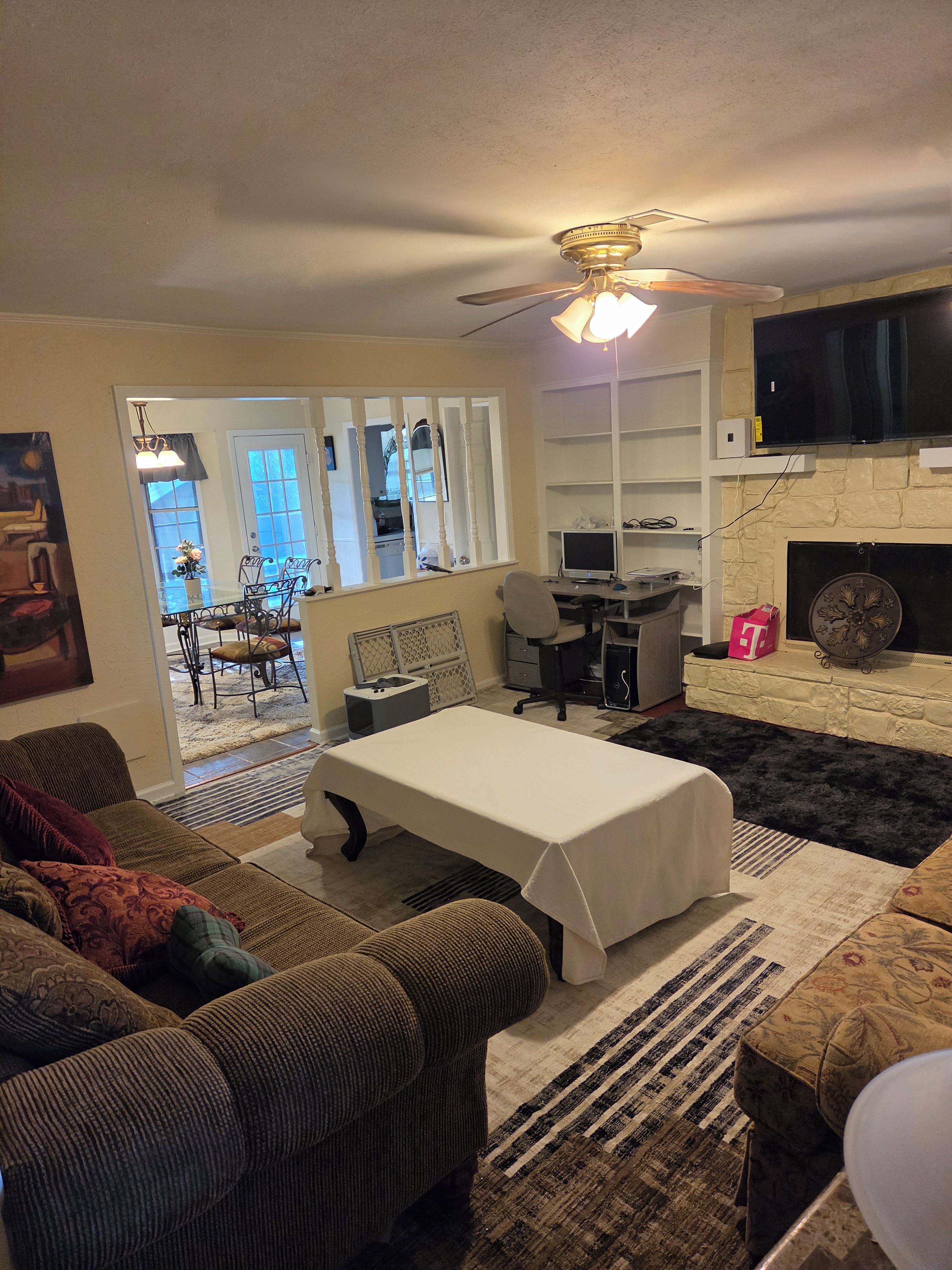 Un salon avec un canapé, une table, un ventilateur de plafond et une cheminée.