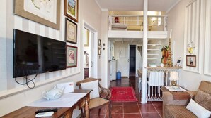A living room with a TV, a sofa, a coffee table, and a dining area with a table and chairs. - COPEL0100 - Prédio 34 (Salvador)
