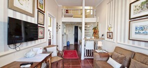 A living room with a TV, a sofa, a coffee table, and a dining area with a table and chairs. - COPEL0100 - Prédio 34 (Salvador)